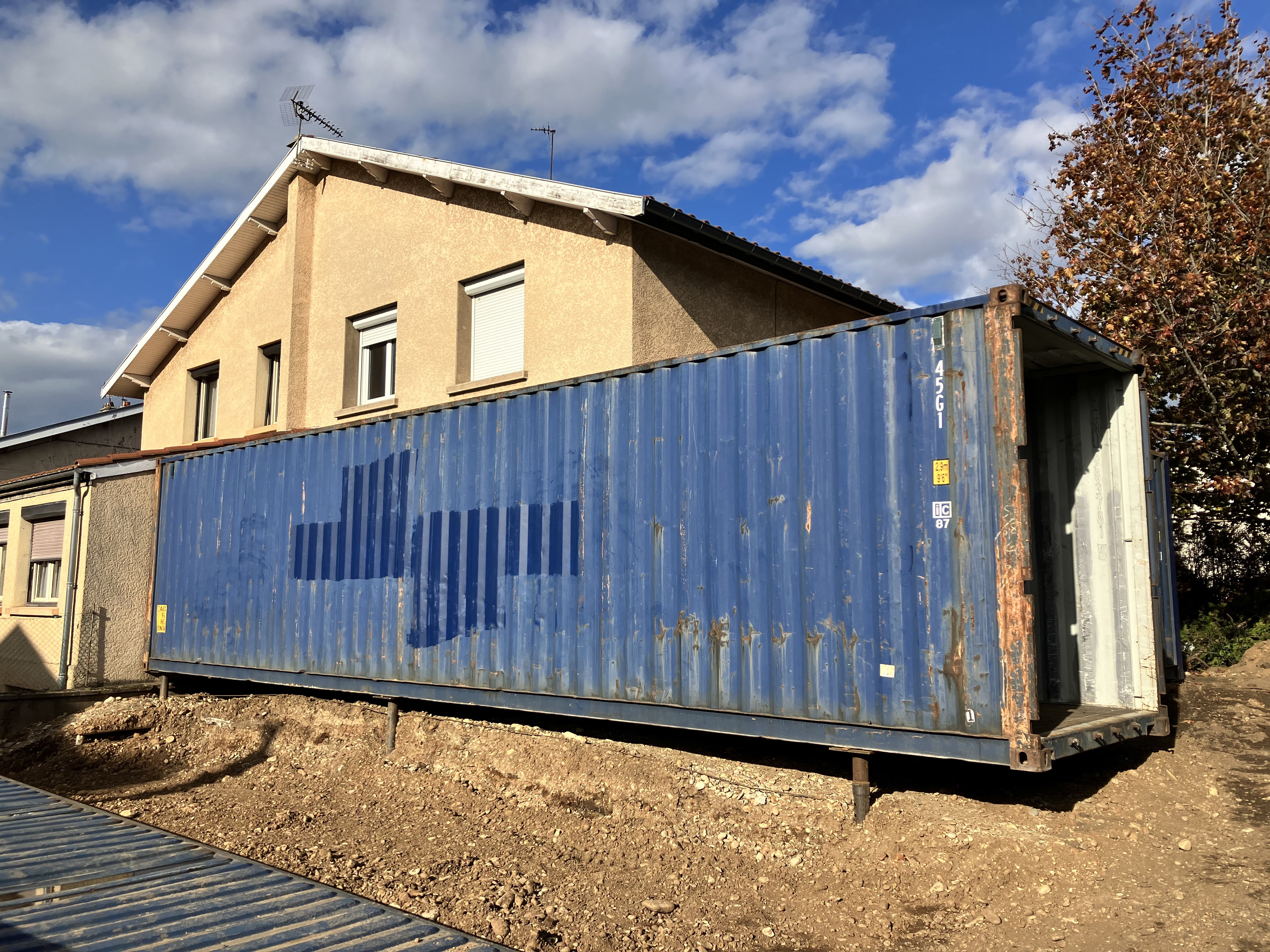 Extension de maison en container, posé dans le jardin de la maison. La photo montre un exemple de fondation sur pieux vissés.